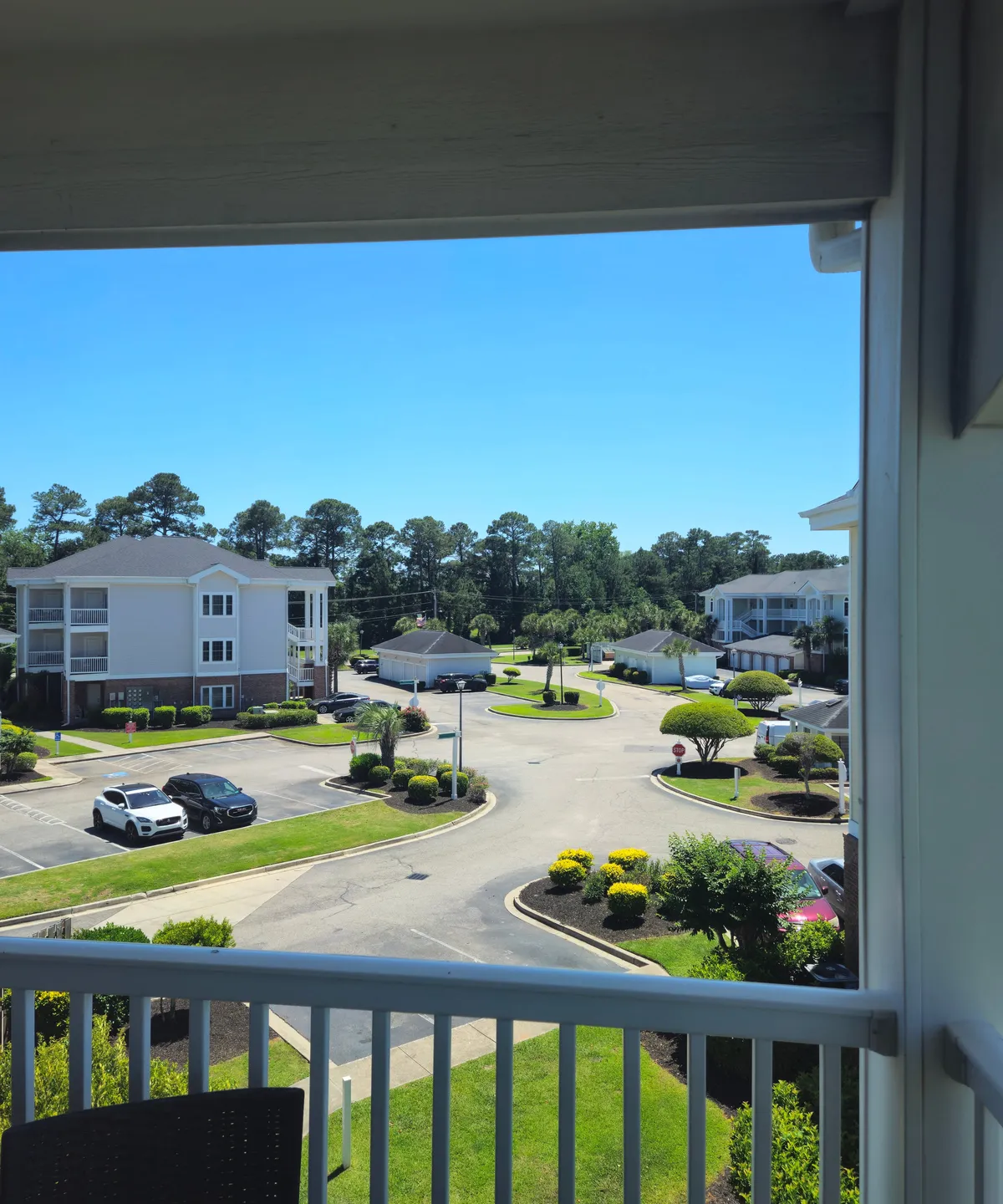 This exterior view showcases neatly landscaped green areas, walking paths, modern apartment buildings, and a bright blue sky. The open, peaceful outdoor spaces evoke the lush, community-oriented feel of a golf community, and the green lawns visually reference the fairways mentioned in the content.