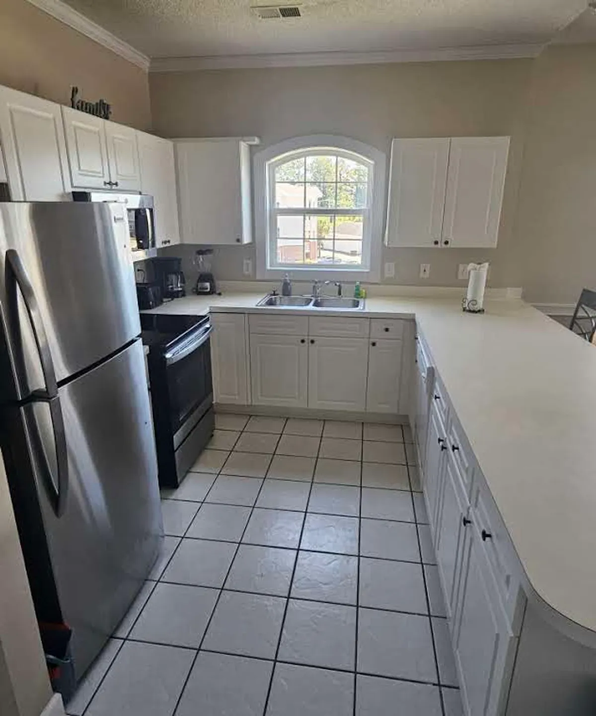 A modern kitchen with a large central island, gleaming stainless steel appliances, and crisp white cabinetry. The setup is perfect for hosting, casual breakfasts, or gathering as friends before heading out on the town.