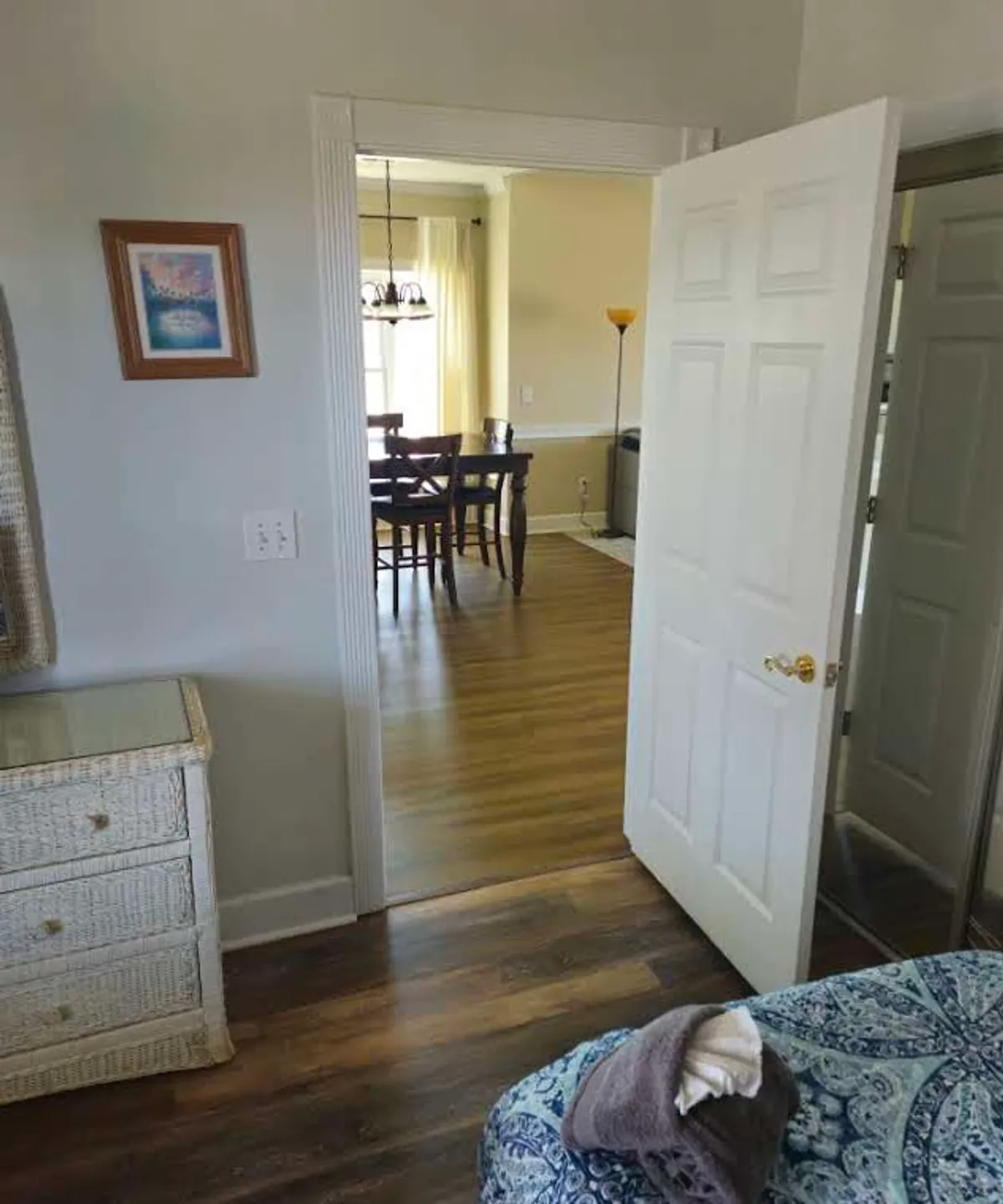 This image looks from a cozy room through a doorway into the dining area, which features a decorative painting on the wall and a welcoming table setup. It hints at laughter-filled meals and the flow between kitchen and dining spaces, supporting the narrative of gathering and sharing meals.