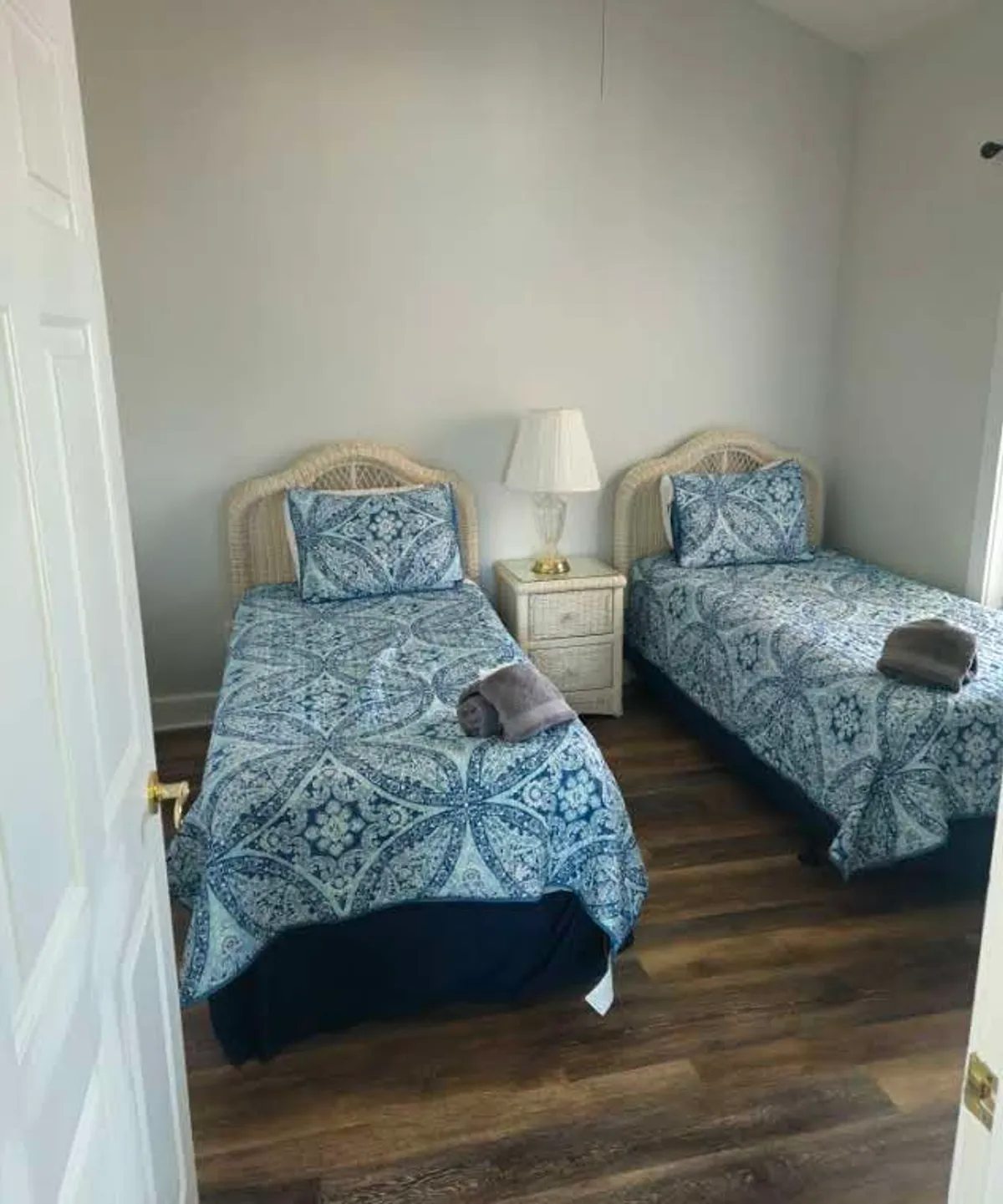 A cheerful bedroom with two twin beds, a nightstand with a lamp, and decorative bedding. The arrangement is perfect for accommodating families or friends, providing both coziness and functionality.